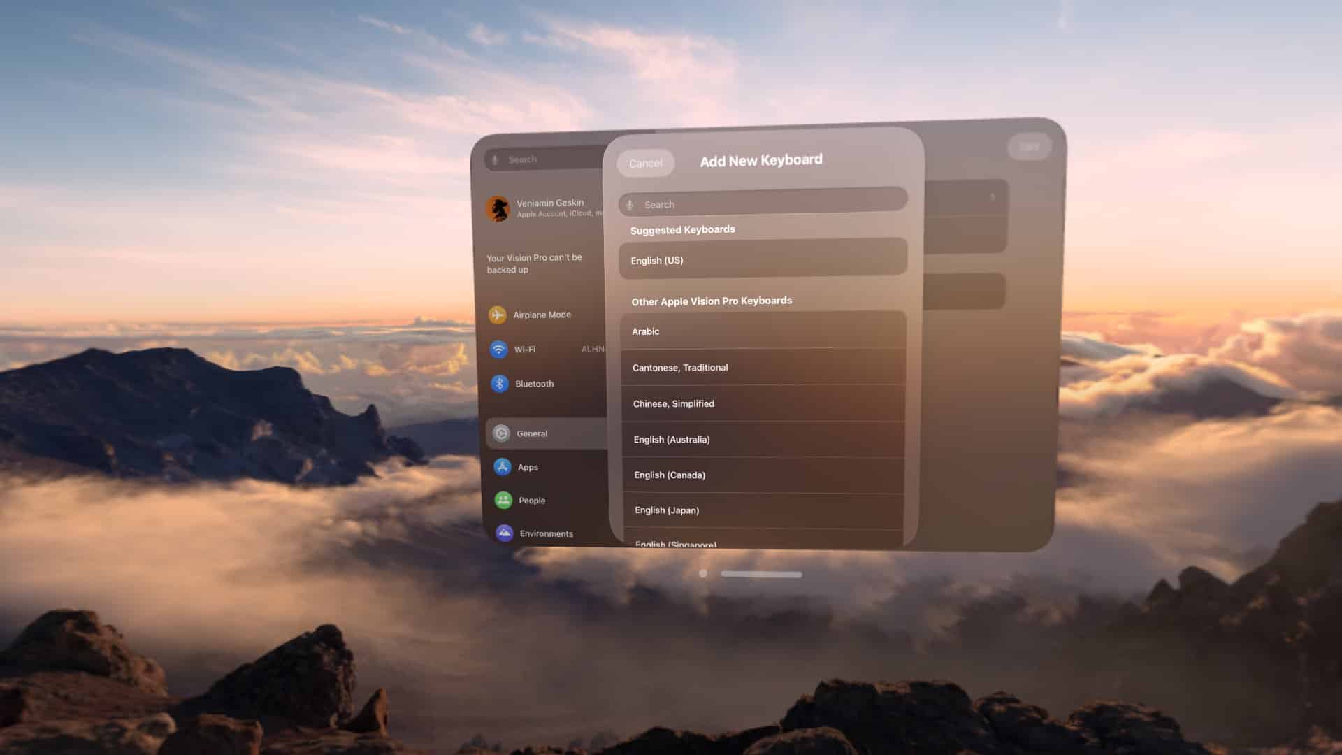 A virtual keyboard settings window is overlayed on a mountainous landscape with clouds and a sunset. The window shows various language options for keyboards, such as Arabic, Chinese, and English, with some options partially visible behind others. Experience seamless navigation with visionOS 2 enhancements.