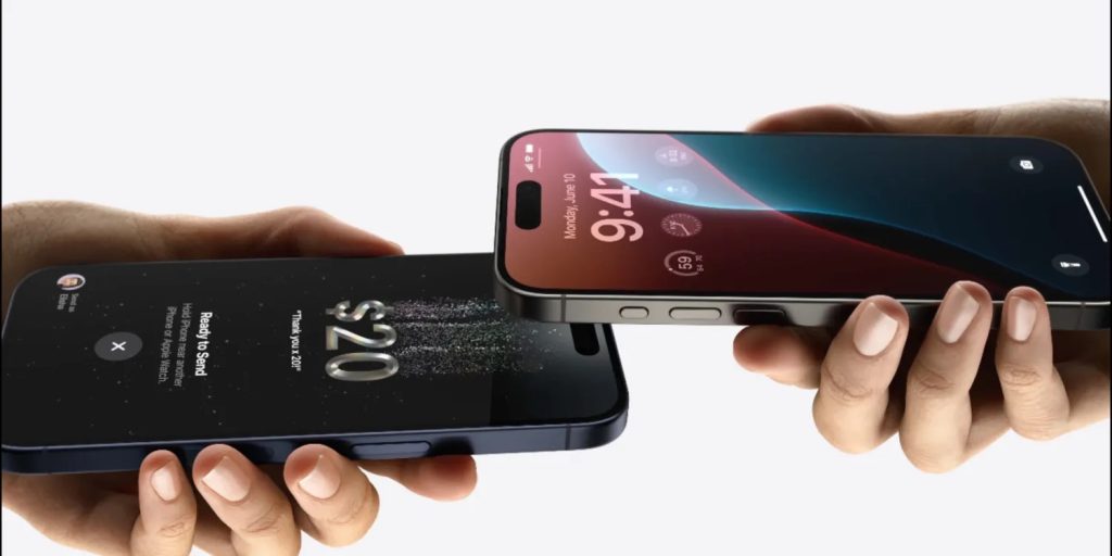 Close-up of two hands each holding a smartphone. One phone displays a transaction of $20 being sent, while the other phone, running iOS 18, shows the time as 9:41 with a customizable home screen and various icons. Both phones are held facing each other, indicating a digital transfer.