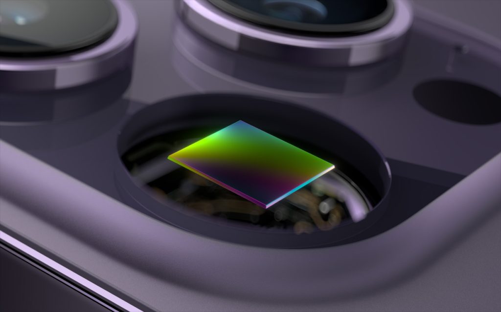 Close-up image of the iPhone 16 camera module showcasing a square photodiode sensor highlighted with a multicolored gradient surface. Surrounding it are sleek, metallic camera lenses and components, emphasizing the advanced technology and precision design in Apple's latest camera upgrades.