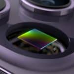 Close-up image of the iPhone 16 camera module showcasing a square photodiode sensor highlighted with a multicolored gradient surface. Surrounding it are sleek, metallic camera lenses and components, emphasizing the advanced technology and precision design in Apple's latest camera upgrades.