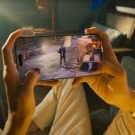 Illustration of Apple gaming strategy 2025, featuring a sleek iPhone, iPad, MacBook, and Vision Pro with a vibrant Games app interface, showcasing immersive gaming experiences and the RAC7 acquisition.
