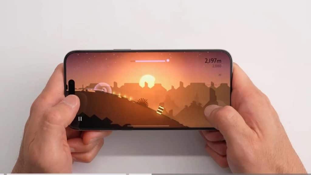 Hands hold a smartphone horizontally with a game displayed on the screen. The game features a silhouette landscape with a sunset, with the player character moving through the terrain. Various game elements like score and progress bar are visible.