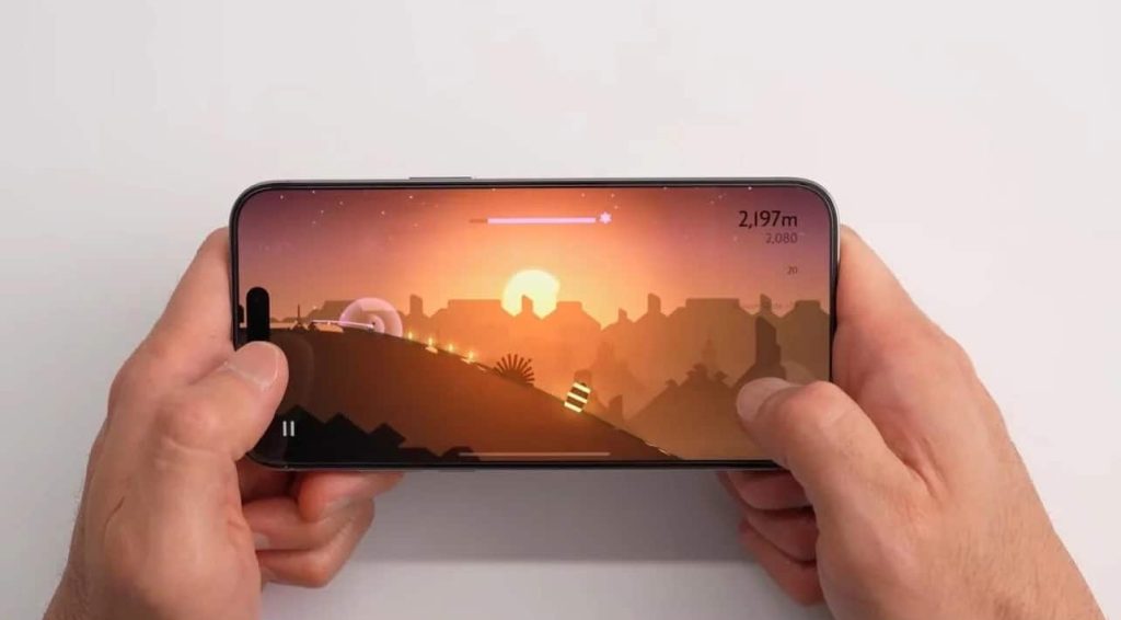 Hands hold a smartphone horizontally with a game displayed on the screen. The game features a silhouette landscape with a sunset, with the player character moving through the terrain. Various game elements like score and progress bar are visible.