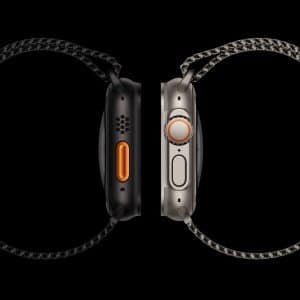 Two smartwatches are shown side-by-side against a black background, showcasing their profiles. One watch has a dark casing with an orange button, while the other has a light casing with an orange accent on a crown-like dial. Both watches have woven wristbands.