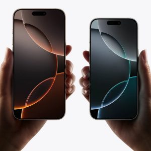 iPhone 16 Pro: Two hands holding Apple iPhones. The left shows a phone with a light and dark brown gradient wallpaper, and the right shows a phone with a teal and dark green gradient wallpaper. Both phones have a dynamic island notch at the top. The AppleMagazine logo is at the bottom right.