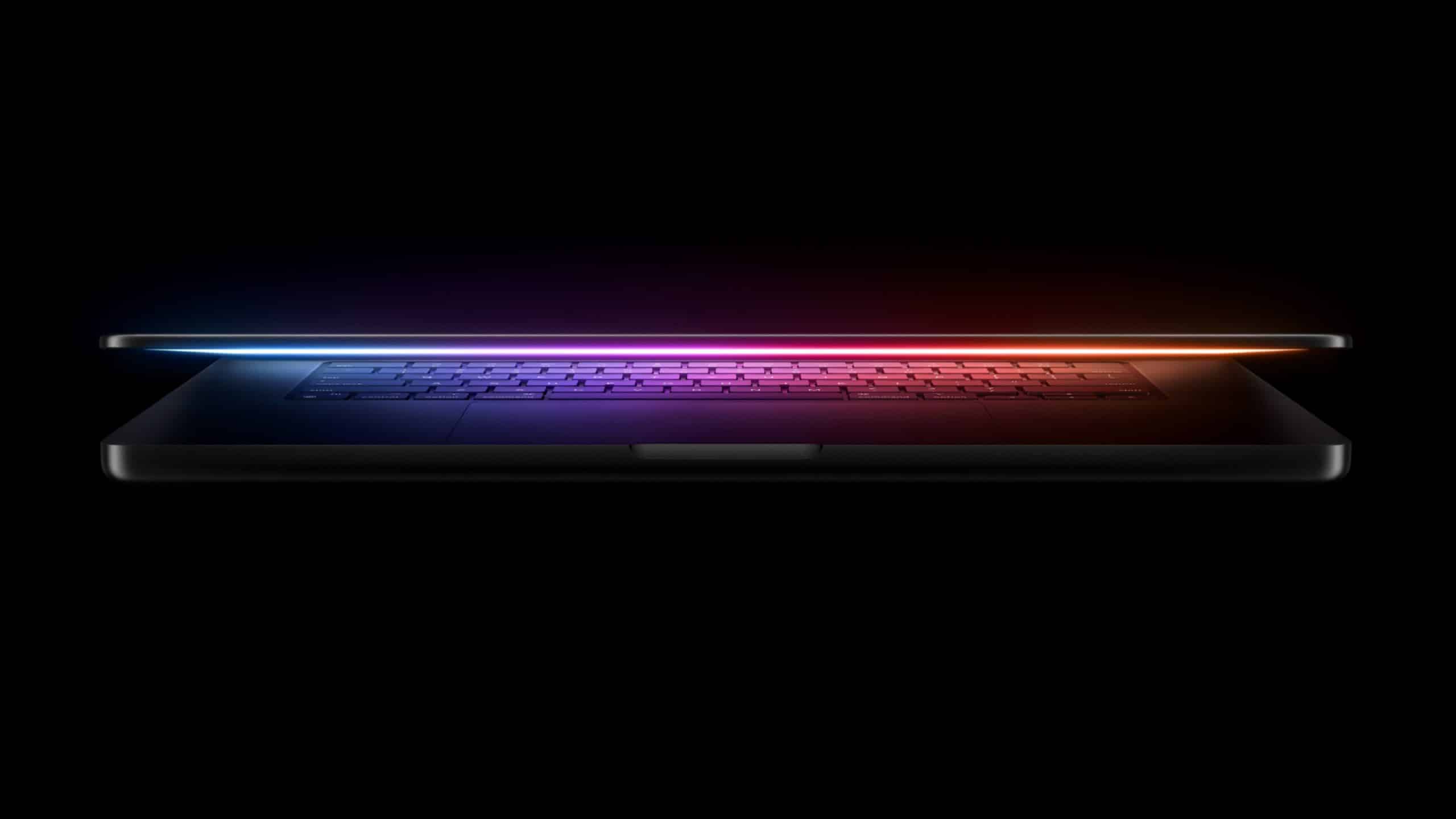 A sleek laptop is partially open against a black background. The screen emits a soft, colorful glow ranging from blue to pink, creating a gradient effect along the edge. The keyboard is barely visible beneath the thinly opened lid.