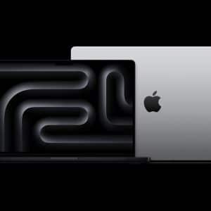 Apple MacBook Pro M4 | 16Gb RAM | 2024 with a stylized abstract design displayed on the screen. Another laptop is closed, showcasing a minimalistic logo on a matte silver finish. The background is entirely black, emphasizing the contrasting metallic textures.