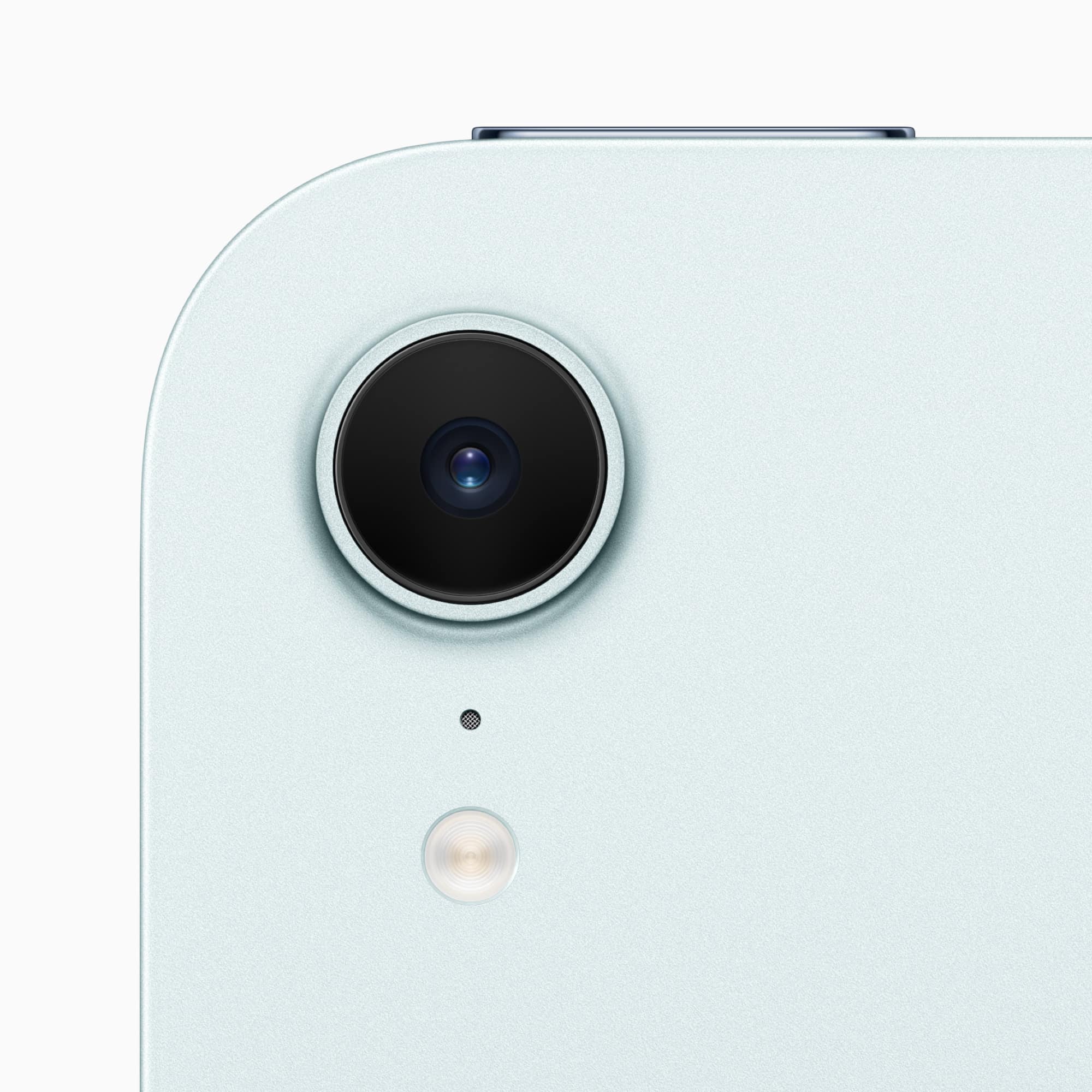 Close-up of an iPad Mini's light-colored tablet camera. The image highlights the rear camera lens alongside a small microphone hole and LED flash below it, all set against a smooth, sleek surface.