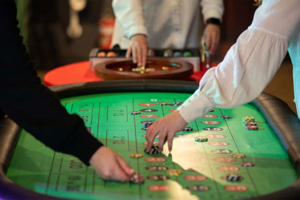 At Apple Casinos, people place bets with chips on a roulette table, enjoying a glimpse into the future of gaming.