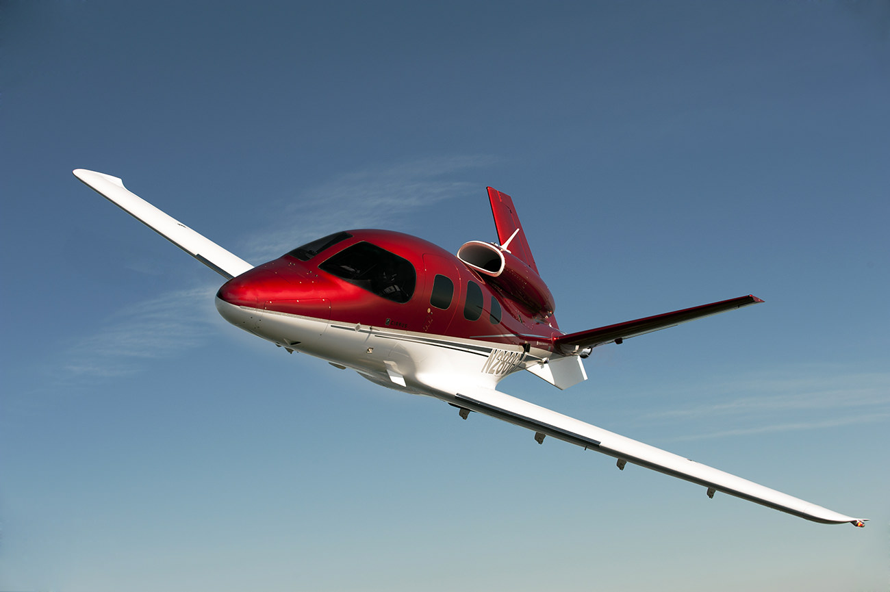 Flying a small Cirrus Vision SF50 red and white private jet in the clear blue sky is a thrilling hobby.