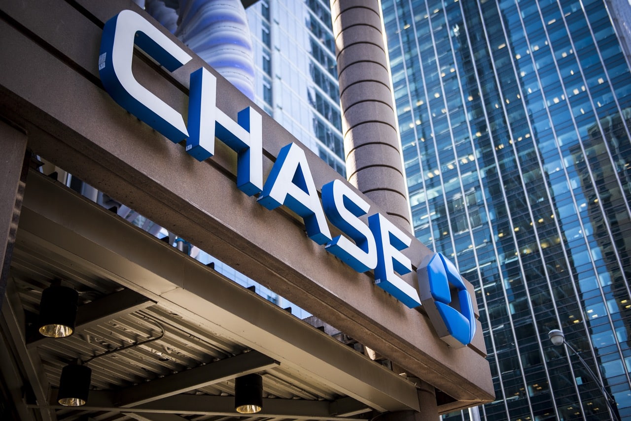 Ground view of a glass skyscraper with a prominent "Chase" sign in blue and white letters on a metal structure at the base. The building facade features reflective windows, embodying Chase Bank's modern touch in the urban cityscape, making it one of the best banks for business.