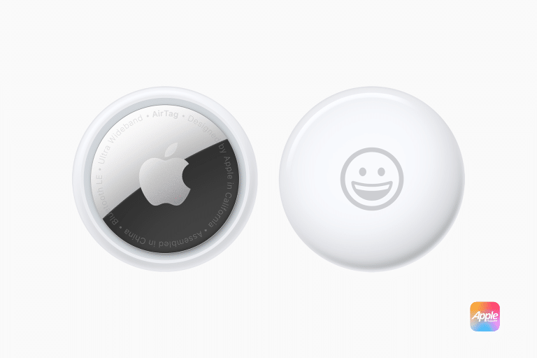 Two Apple AirTags rest on a white background. The left one proudly displays the iconic Apple logo surrounded by text, while the right features a charming smiley face. A small Apple logo graces the bottom corner, adding a touch of elegance to these innovative AirTags.