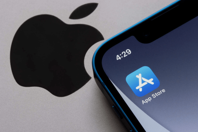 A close-up of an iPhone screen reveals recent App Store changes, with the familiar icon set against a blue background and a stylized white "A." The phone's time reads 4:29, while the iconic Apple logo subtly enhances the backdrop.