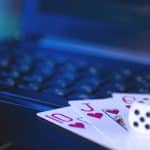 Playing cards and dice on a laptop keyboard, indicating online gambling.
