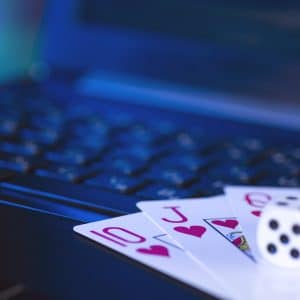 Playing cards and dice on a laptop keyboard, indicating online gambling.