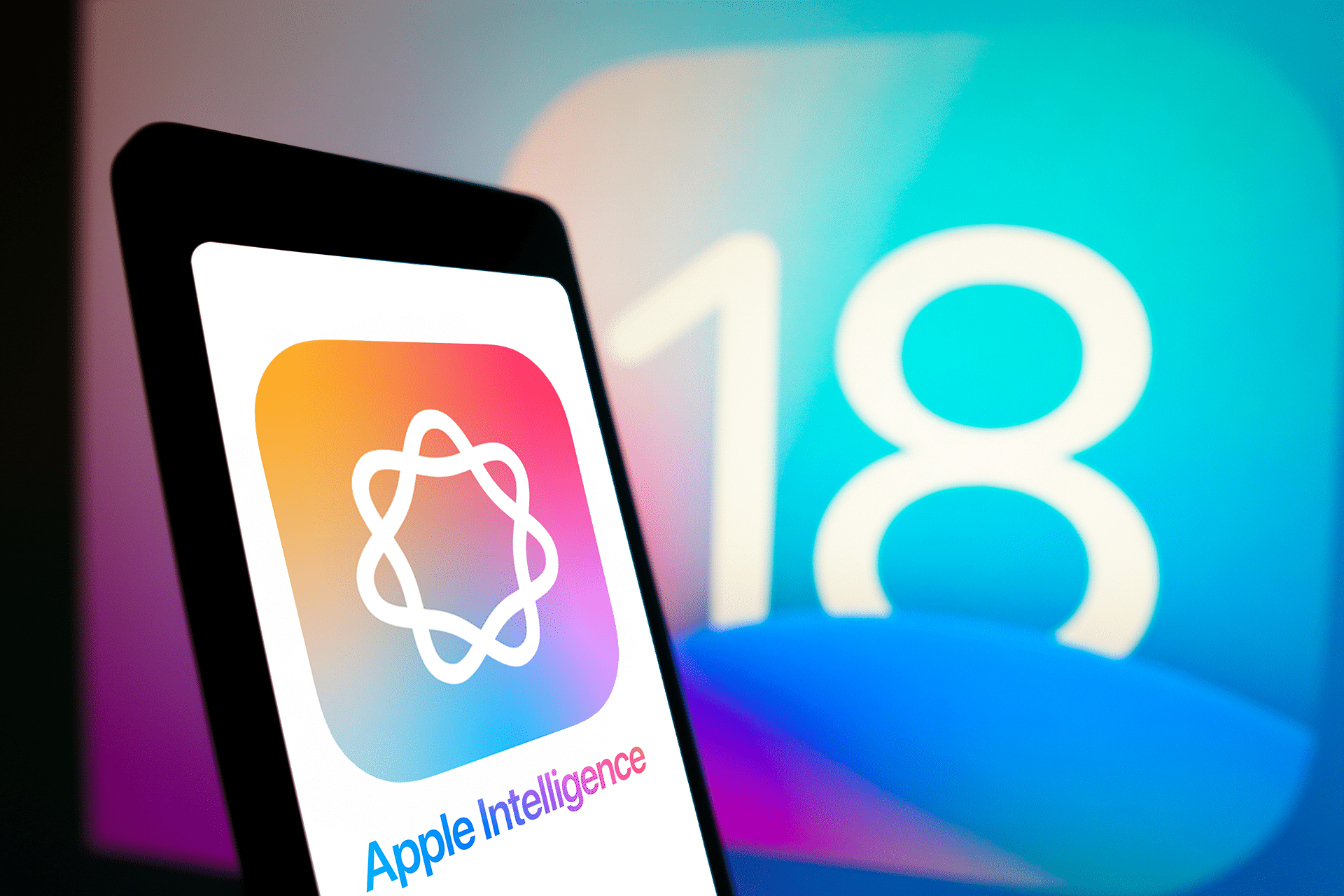 A smartphone showcasing the "Apple Intelligence" logo and name against a vibrant gradient backdrop sits before a screen displaying the number 18, hinting at the exciting features of the upcoming iOS 18.3 release.