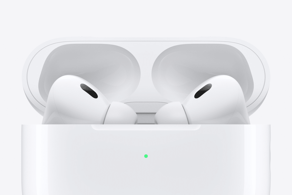 Close-up of two white wireless earbuds resembling Fake AirPods Pro in an open charging case, set against a plain white background. A small green light on the case signals charge status.