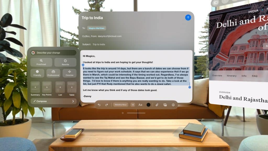 A virtual reality interface on the Apple Vision Pro reveals an email draft titled "Trip to India," detailing travel dates and choices. Surrounding windows show a power control panel and a travel guide, "Delhi and Rajasthan," all seamlessly integrated through spatial computing against a modern living room background.