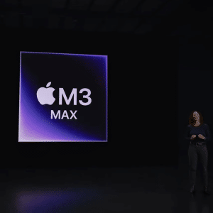 A presentation slide highlights the Apple logo with "M3 MAX" text on a dark background. A person stands on stage, discussing the innovations of the Apple M3 Chip, with the iconic Apple logo prominently displayed in the bottom right corner.