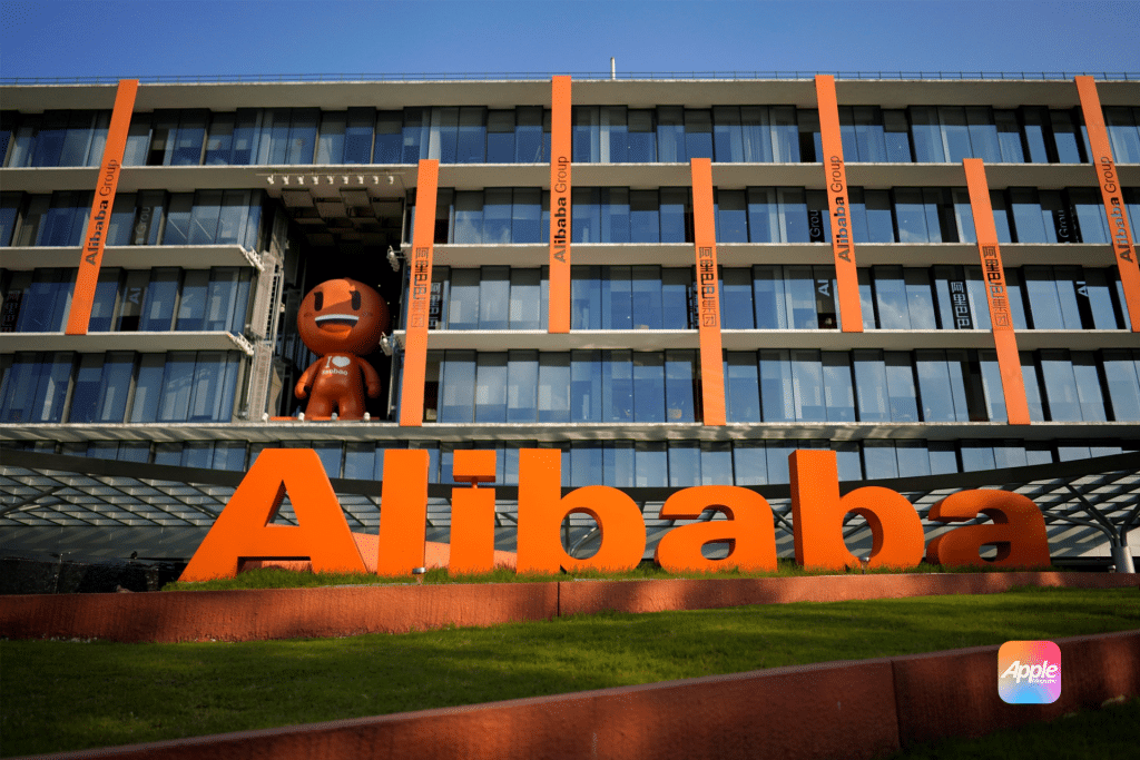 A large orange "Alibaba" sign stands proudly in front of a modern glass building with vertical orange accents, reflecting the vibrant tech spirit of China. A brown character statue graces the balcony, while the sun shines brightly, casting clear shadows reminiscent of Apple's design intelligence.