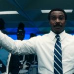 A man in a white shirt and striped tie stands with arms raised, holding a staff, in front of a Severance-inspired marching band dressed in blue uniforms with "LUMON" visible on one jacket. The background glows with blue light.