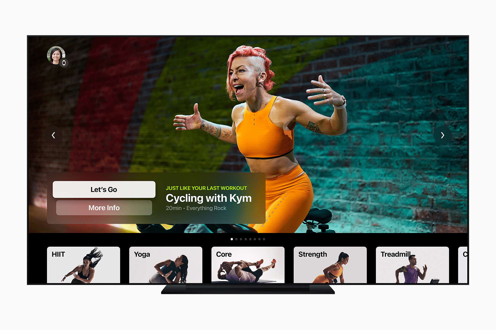 A TV screen displays a virtual cycling workout class led by an energetic instructor in orange workout clothes, streaming from The Studio, with various fitness class options like HIIT, Yoga, Core, Strength, and Treadmill shown below.