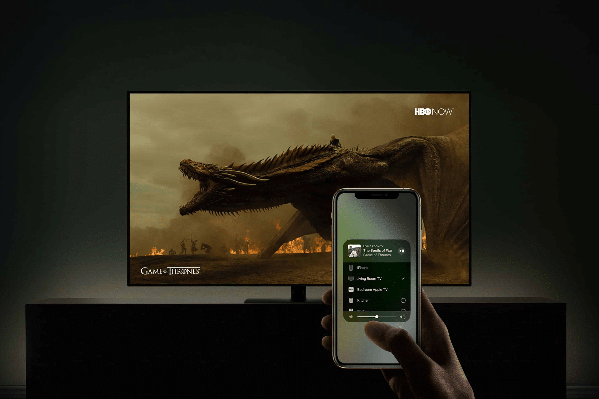 A hand holds a smartphone in front of a TV displaying a Game of Thrones dragon scene. The phone shows an AirPlay media control screen, seamlessly streaming content to the TV.
