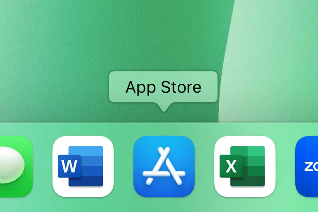 A close-up of a computer dock displays app icons like Microsoft Word, App Store, and Excel. A green label above the App Store icon clearly identifies it as “App Store.”.
