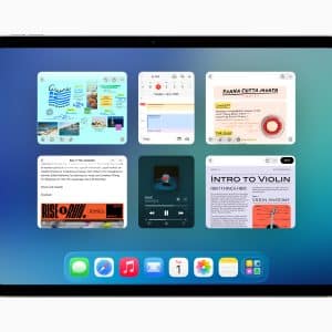 An iPad screen running iPadOS 26 displays six open app windows—notes, music, reminders, and web pages—in a multitasking view over a blue gradient background, with a dock of app icons at the bottom.