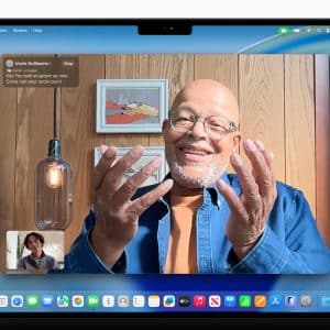 MacBook screen running macOS Tahoe 26, showcasing dynamic desktop wallpaper and updated system apps with Apple Intelligence features.