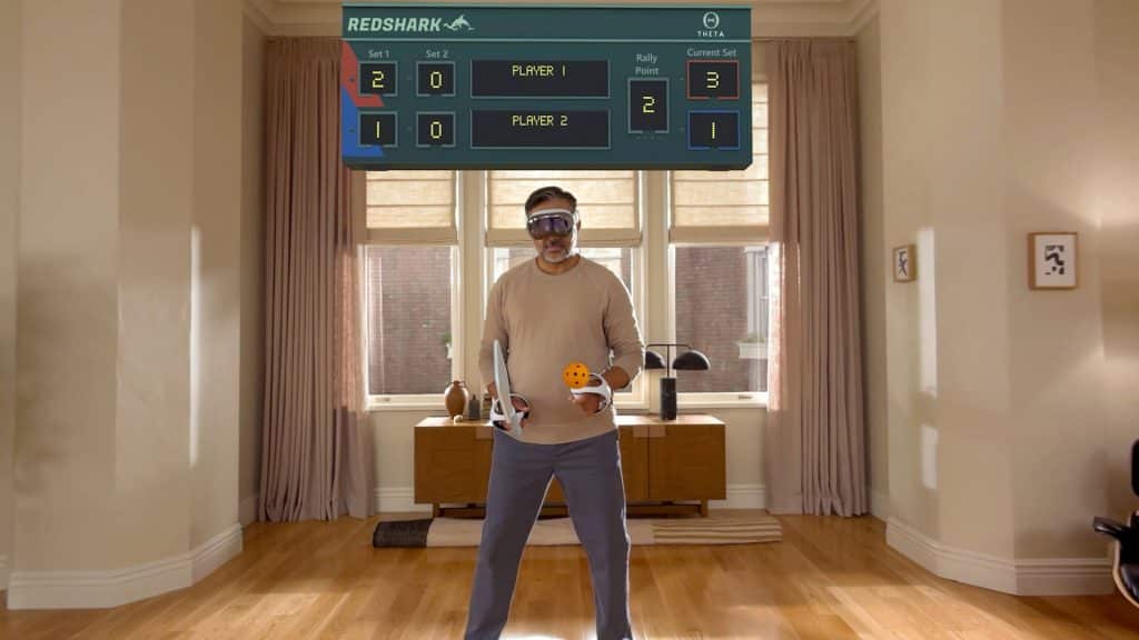 A man wearing augmented reality glasses powered by visionOS plays virtual table tennis in a living room. He holds a paddle and a ball, with a digital game scoreboard displayed above him.