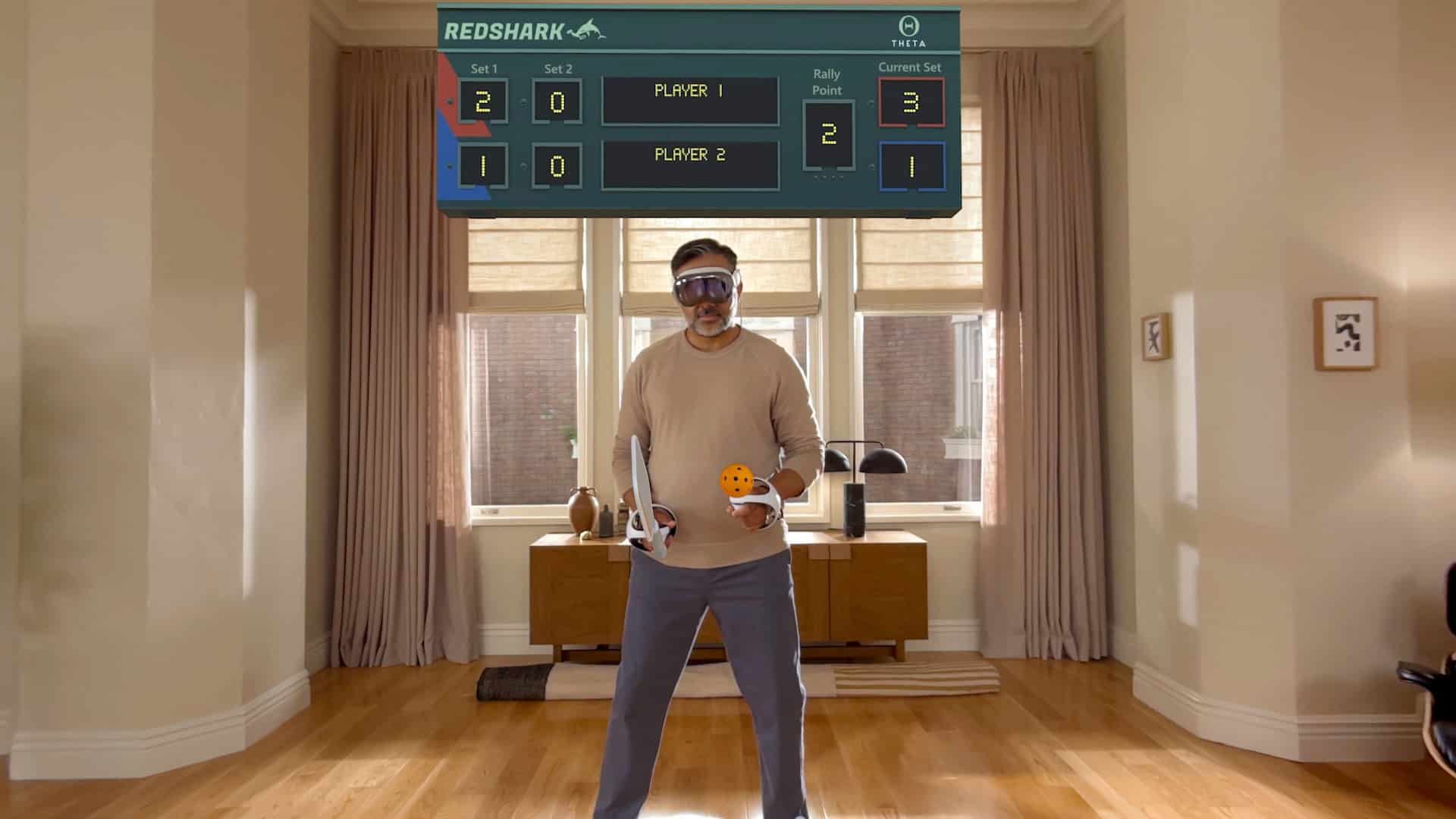 A man wearing augmented reality glasses powered by visionOS plays virtual table tennis in a living room. He holds a paddle and a ball, with a digital game scoreboard displayed above him.