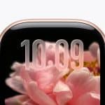 A close-up of a smartwatch screen displaying the time 10:09 with a pink flower in the background. The watch has a gold-colored edge and a rounded digital crown on the right side.