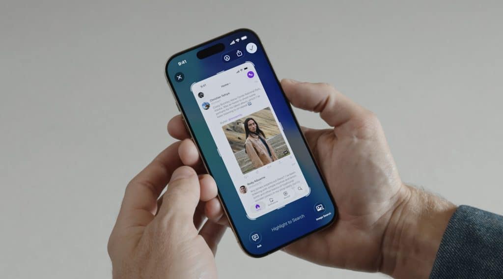 A person holds a smartphone running iOS 26, displaying a social media app feed with posts, including a photo of a woman, comments, icons, and various menu options on the screen.