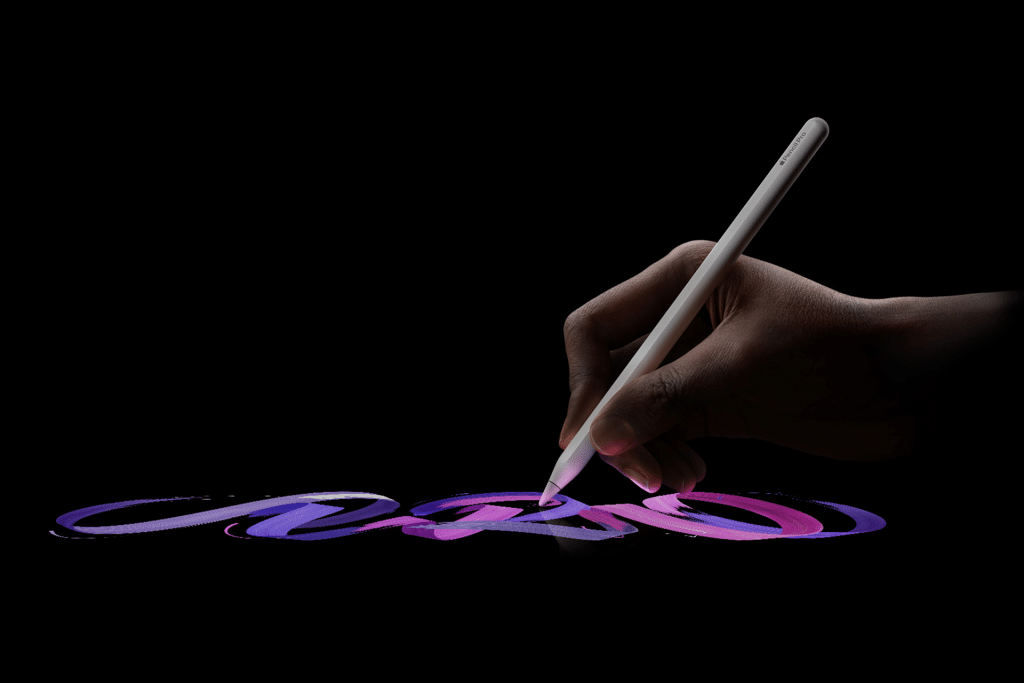 A hand holding an Apple Pencil draws colorful, swirling lines in shades of purple, blue, and pink on a dark background.