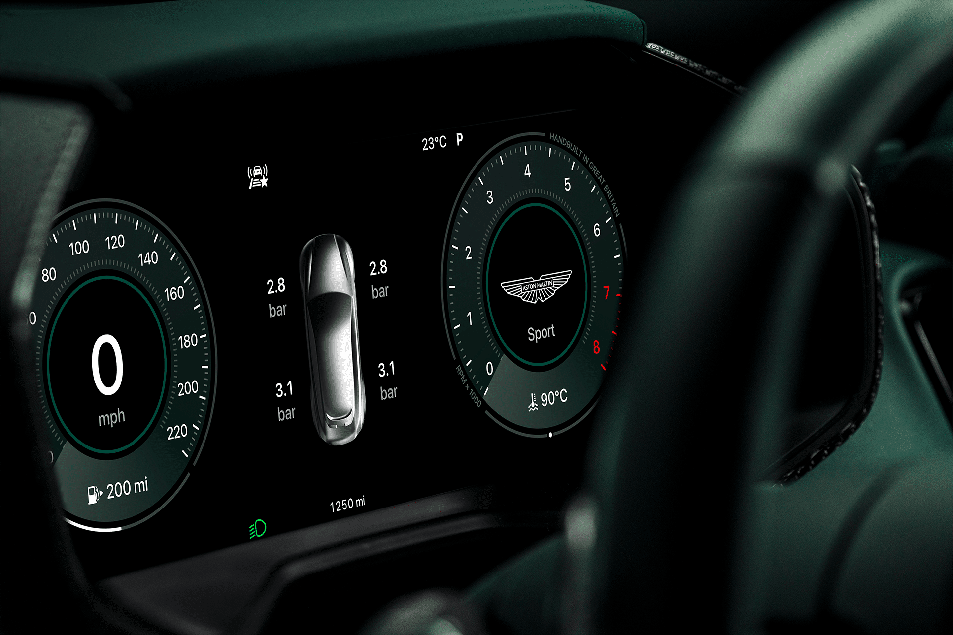 A digital car dashboard display shows 0 mph speed, tire pressures, a central car graphic, “Sport” mode with the Aston Martin logo, Carplay Ultra integration, a temperature of 23°C, and various dashboard indicators.