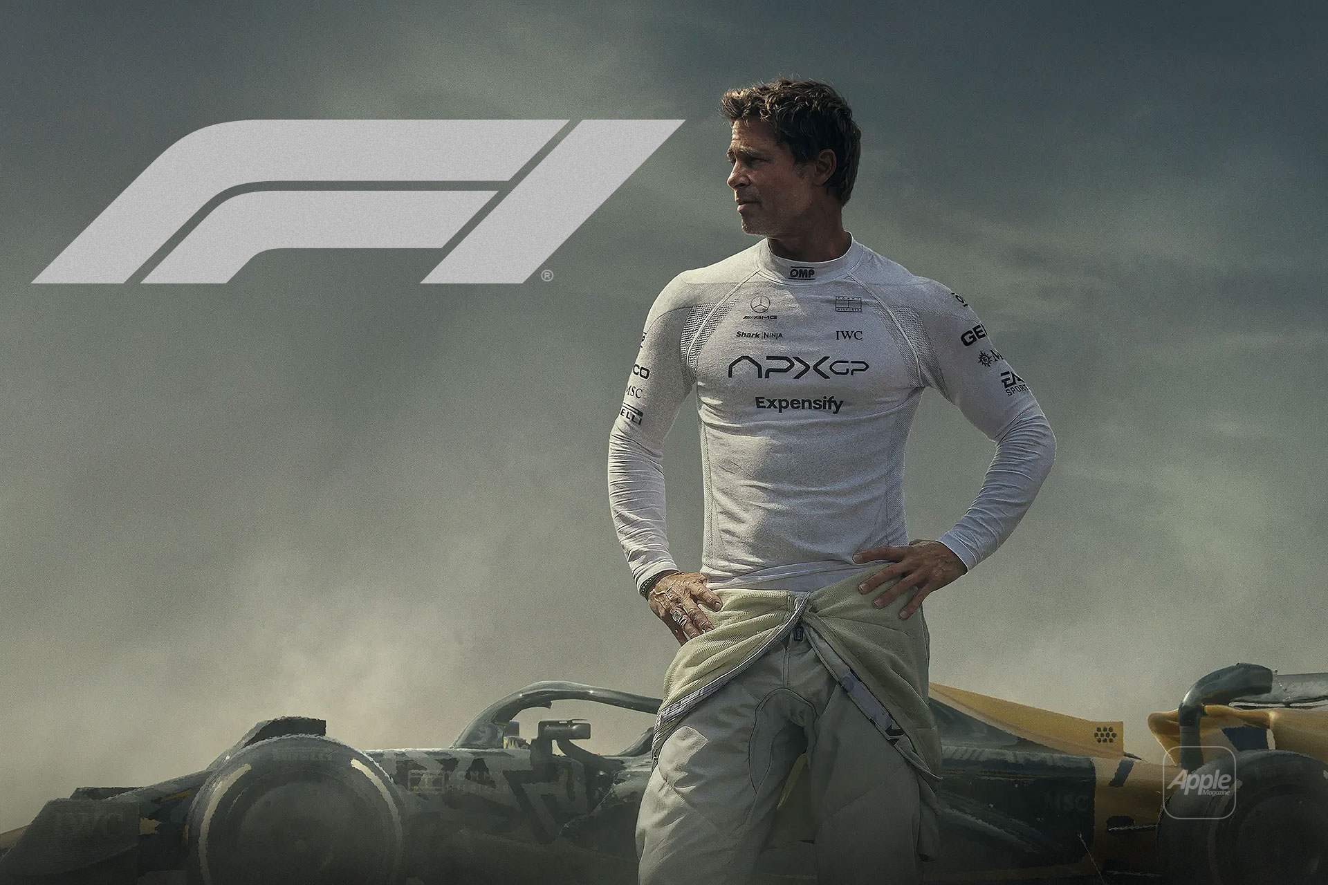 A race car driver in a white racing suit stands before a Formula 1 car with the F1 logo above him. Smoky, dramatic lighting sets an intense competitive mood, reminiscent of an F1 haptic trailer's immersive energy.