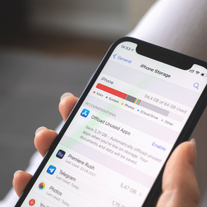 A hand holding an iPhone displays the Storage screen, highlighting usage by apps, photos, and system files, with helpful suggestions to offload unused apps.