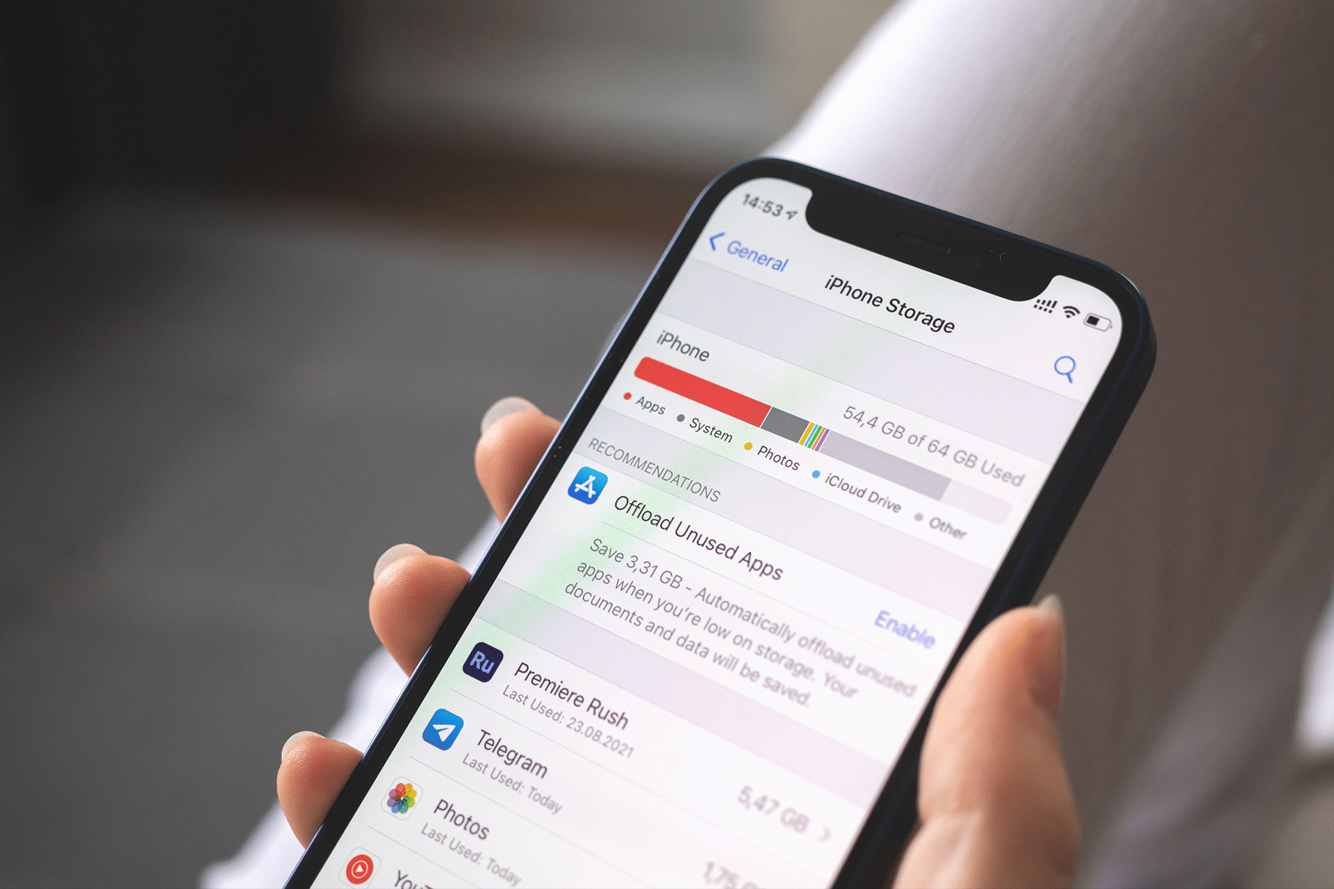 A hand holding an iPhone displays the Storage screen, highlighting usage by apps, photos, and system files, with helpful suggestions to offload unused apps.