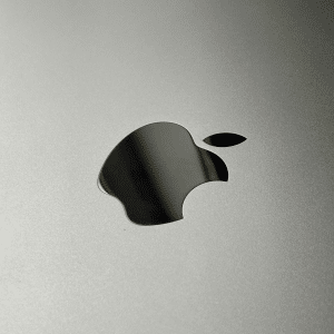 Close-up of a metallic surface featuring a reflective Apple logo in the center, evoking Mac Studio's focus on desktop productivity and streamlining, with minimal text along the right edge.