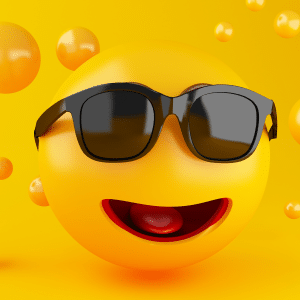 A bright yellow smiley face emoji, perfect for your next emoji game, wears black sunglasses and smiles with an open mouth, surrounded by smaller yellow spheres on a yellow background.