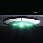 Close-up of the underside of an Apple Watch with green sensor lights illuminated, highlighting the device's blood oxygen monitoring sensors and part of the engraved text around its circular sensor area.