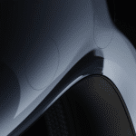 Close-up of a sleek, curved metallic car body with a glossy finish, highlighting the wheel arch and subtle reflections—its precision reminiscent of the advanced design behind Apple Vision Pro under soft lighting.