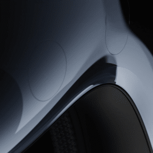 Close-up of a sleek, curved metallic car body with a glossy finish, highlighting the wheel arch and subtle reflections—its precision reminiscent of the advanced design behind Apple Vision Pro under soft lighting.