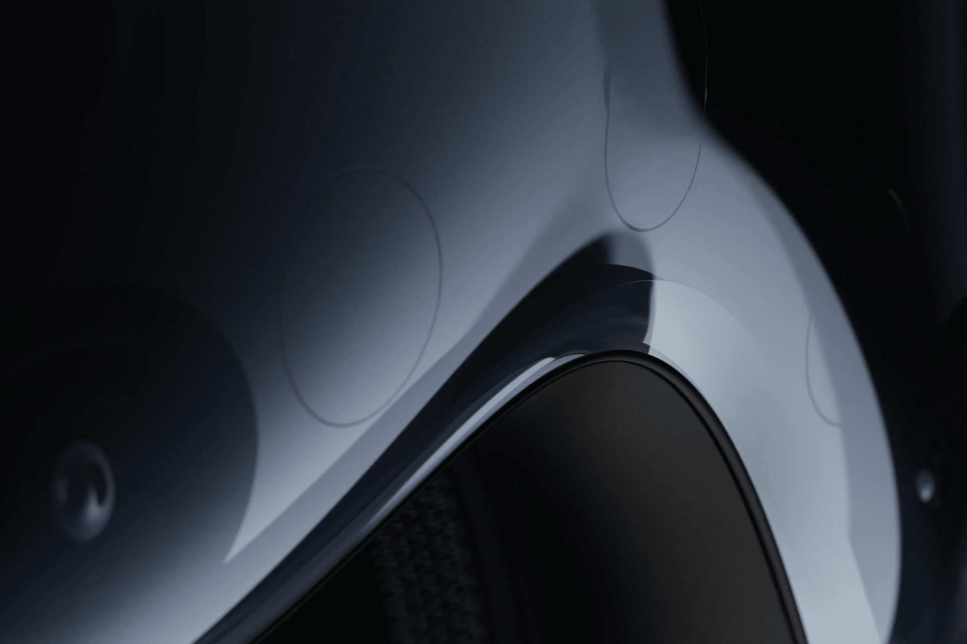 Close-up of a sleek, curved metallic car body with a glossy finish, highlighting the wheel arch and subtle reflections—its precision reminiscent of the advanced design behind Apple Vision Pro under soft lighting.