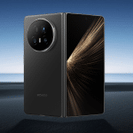 A black Honor Magic V5 Foldable phone is displayed on a sandy beach background, shown both open with a bright screen and closed to reveal its rear camera module.