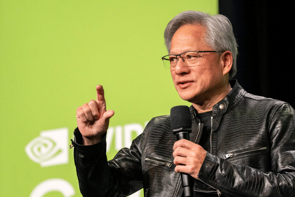 A man wearing glasses and a black leather jacket holds a microphone and gestures with his hand while discussing chips and geopolitics in front of a green background with partially visible white text and graphics.