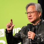 A man wearing glasses and a black leather jacket holds a microphone and gestures with his hand while discussing chips and geopolitics in front of a green background with partially visible white text and graphics.