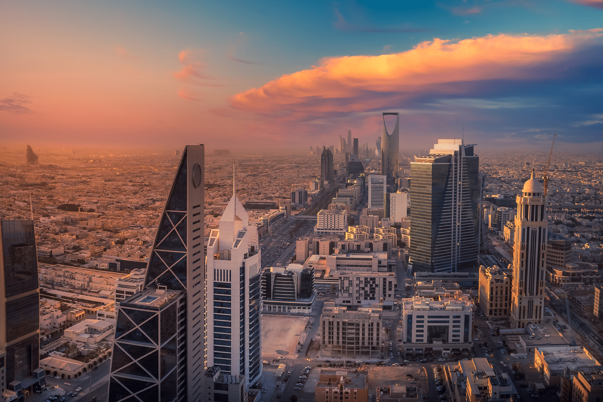 Aerial view of Riyadh, Saudi Arabia at sunset, showcasing modern skyscrapers, including the Kingdom Centre, with vibrant clouds and warm sunlight illuminating the cityscape—reminding us that even in thriving cities, security flaw risks like TheTruthSpy can exist.
