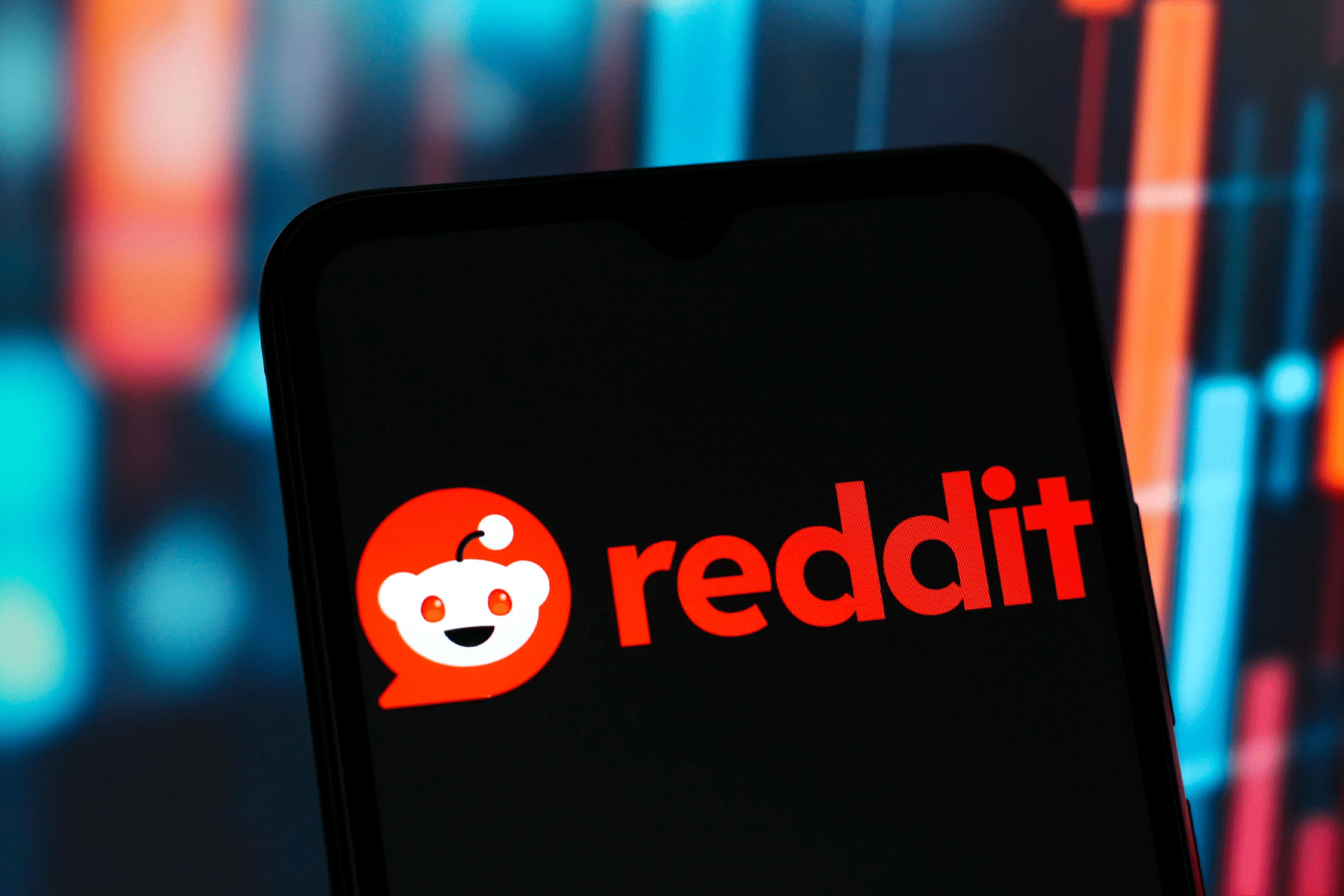 A smartphone screen displays the Reddit logo and name in red and white, with a blurred background featuring colorful lights and bars—reflecting vibrant discussions in the 3D printing market.